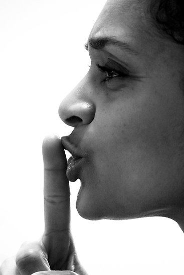 A woman with her finger over her mouth as if to say shhhh!