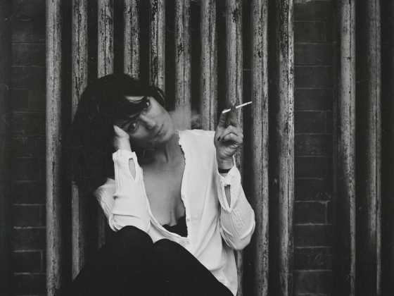 Woman sits smoking cigarette looking 'French'