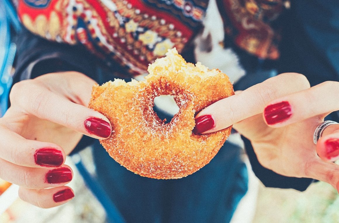 Woman holding sugary doughnut