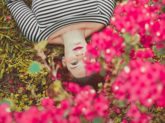 Woman laying in a bed of Spring flowers with stripy top