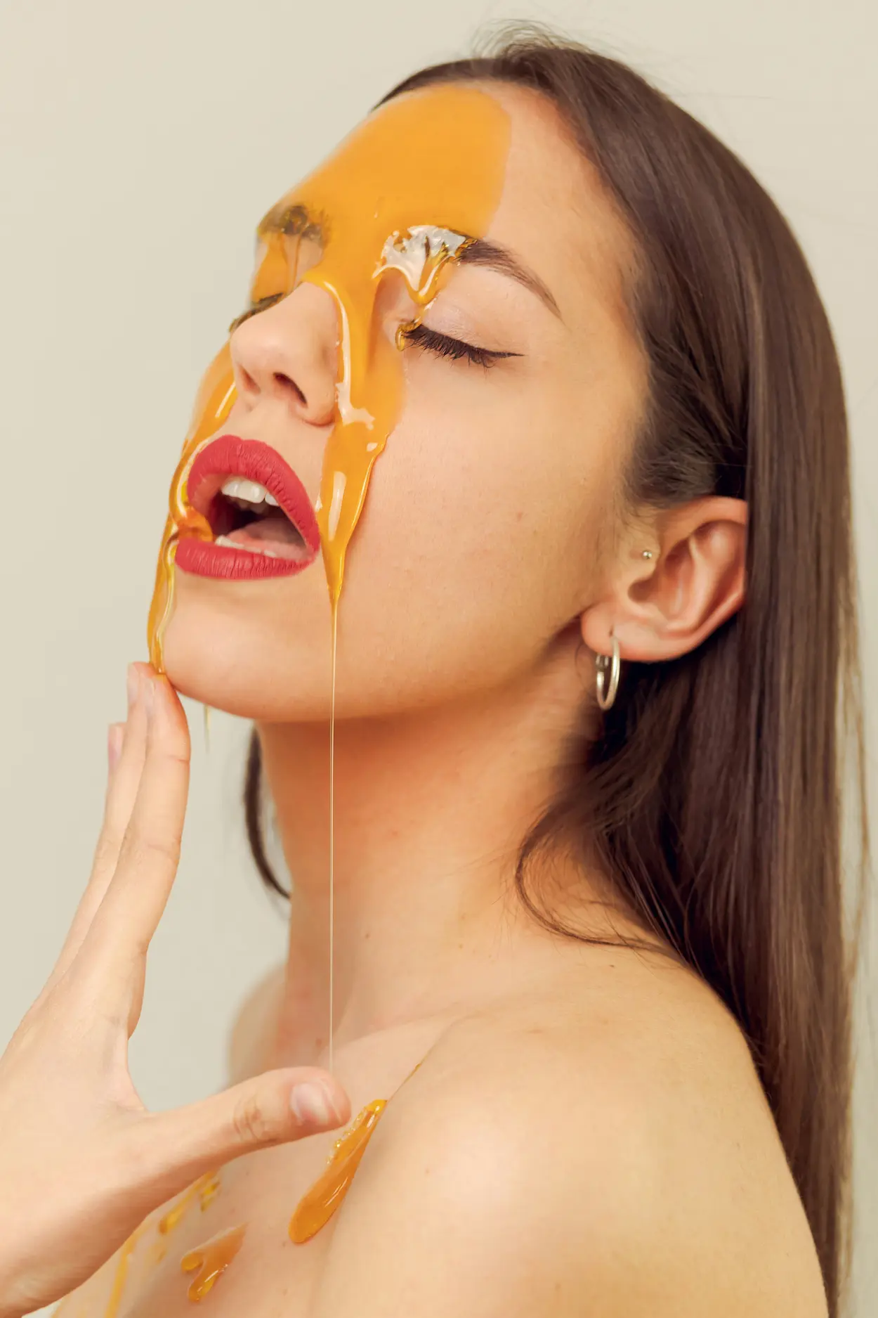 Beauty extremes, woman with dripping honey on face.