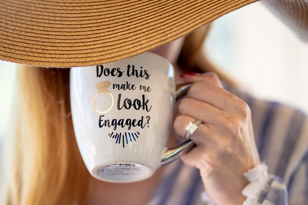 Woman wearing engagement ring and holding cup